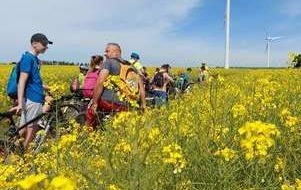 Uczestnicy rajdu na  tle pola rzepaku