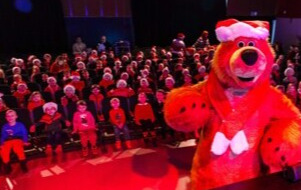 Na zdjęciu niedźwiadek oraz przedszkolaki na widowni