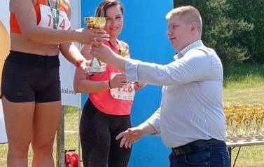 Na zdjęciu widać sekretarza gminy, kt&oacute;ry wręcza puchary zawodniczkom stojącym na podium 