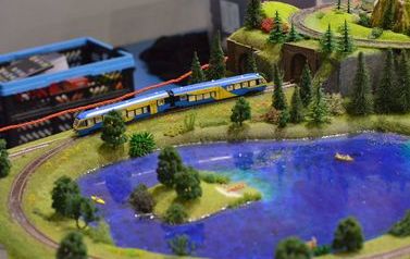 Zdjęcie prezentuje miniaturową kolej oraz sztuczne jezioro na makiecie 